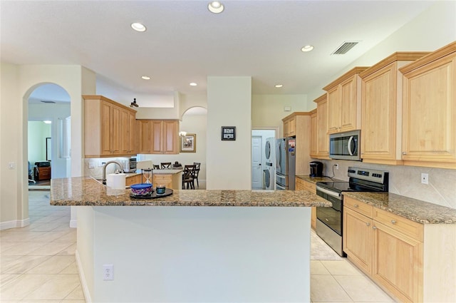 208 147th St NE, Bradenton, FL 34212 - kitchen featuring stainless steel appliances, arched walkways, light tile patterned floors, light brown cabinetry, and recessed lighting