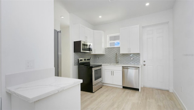 4796 Duncan Rd, Punta Gorda, FL 33982 - kitchen with stainless steel appliances, white cabinets, light wood finished floors, backsplash, and recessed lighting