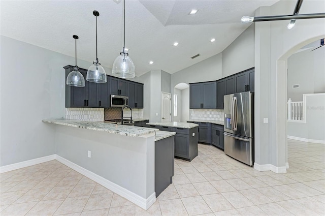 6423 Royal Tern Cir, Lakewood Ranch, FL 34202 - kitchen with appliances with stainless steel finishes, arched walkways, a peninsula, decorative backsplash, and light stone countertops
