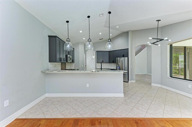 6423 Royal Tern Cir, Lakewood Ranch, FL 34202 - kitchen with stainless steel appliances, lofted ceiling, decorative backsplash, a chandelier, and light tile patterned floors