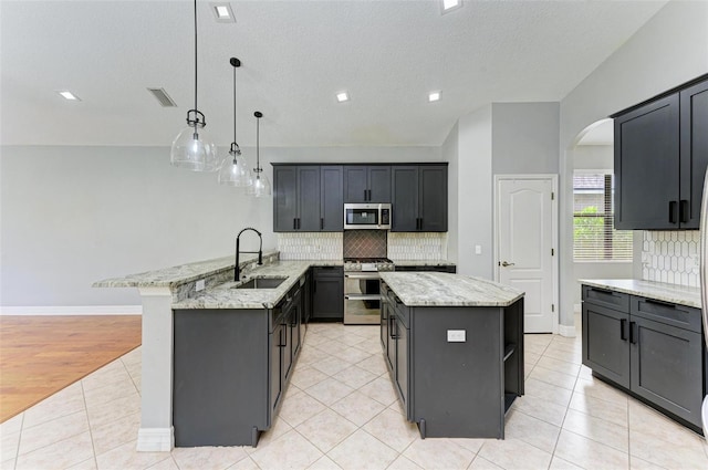 6423 Royal Tern Cir, Lakewood Ranch, FL 34202 - kitchen with stainless steel appliances, a peninsula, tasteful backsplash, light stone counters, and light tile patterned floors
