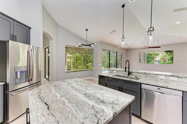 6423 Royal Tern Cir, Lakewood Ranch, FL 34202 - kitchen featuring stainless steel appliances, lofted ceiling, arched walkways, a kitchen island, and light stone counters