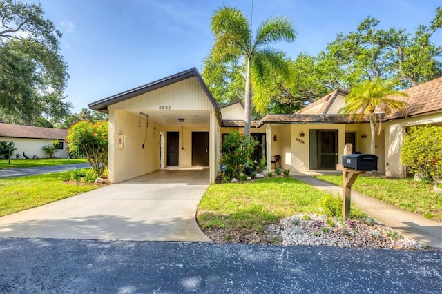 6832 Woodwind Dr Unit 53, Sarasota, FL 34231 - view of front of house with a carport, driveway, stucco siding, and a front yard