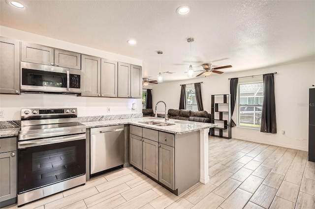 718 17th St E, Bradenton, FL 34208 - kitchen featuring stainless steel appliances, a peninsula, ceiling fan, open floor plan, and wood tiled floors