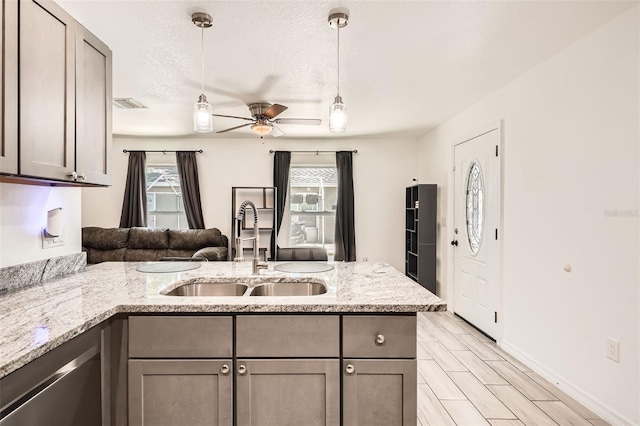 718 17th St E, Bradenton, FL 34208 - kitchen featuring dishwasher, a peninsula, ceiling fan, decorative light fixtures, and light stone counters