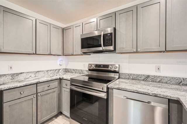 718 17th St E, Bradenton, FL 34208 - kitchen featuring stainless steel appliances, gray cabinets, and light stone countertops