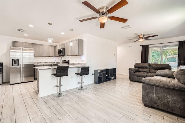 718 17th St E, Bradenton, FL 34208 - kitchen featuring appliances with stainless steel finishes, a ceiling fan, open floor plan, a peninsula, and a kitchen bar