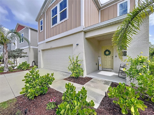 12832 Oak Hill Way, Parrish, FL 34219 - doorway to property featuring board and batten siding, a garage, stucco siding, and concrete driveway