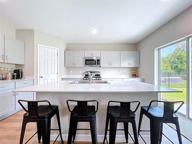 12832 Oak Hill Way, Parrish, FL 34219 - kitchen with stainless steel appliances, light countertops, a breakfast bar, a kitchen island with sink, and light wood finished floors