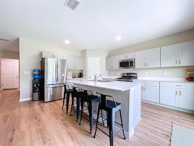 12832 Oak Hill Way, Parrish, FL 34219 - kitchen with stainless steel appliances, a breakfast bar, light wood-type flooring, a kitchen island with sink, and light countertops