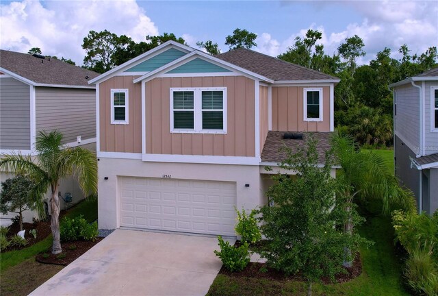 12832 Oak Hill Way, Parrish, FL 34219 - view of front of property with board and batten siding, an attached garage, concrete driveway, and roof with shingles