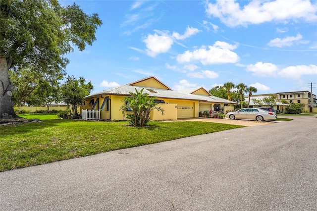 20 Idle Sands Dr, Venice, FL 34293 - view of front facade with an attached garage, driveway, a front lawn, stucco siding, and a tile roof