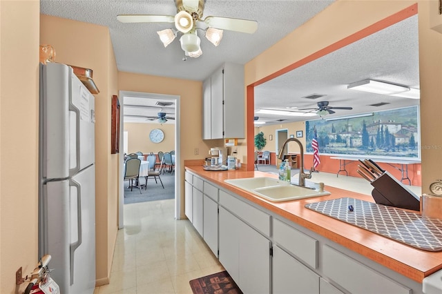 20 Idle Sands Dr, Venice, FL 34293 - kitchen with freestanding refrigerator, a ceiling fan, a textured ceiling, light countertops, and white cabinetry