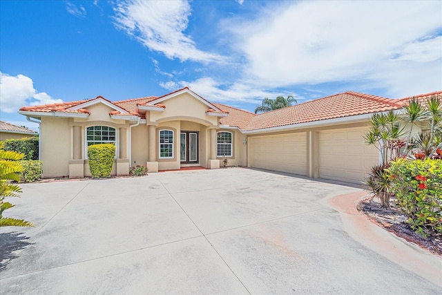 5523 Secluded Oaks Way, Sarasota, FL 34233 - mediterranean / spanish-style house featuring driveway, a garage, a tile roof, stucco siding, and french doors