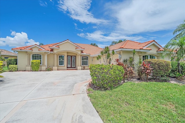 5523 Secluded Oaks Way, Sarasota, FL 34233 - mediterranean / spanish home featuring french doors, a tile roof, stucco siding, and driveway