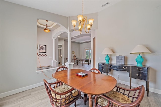 5523 Secluded Oaks Way, Sarasota, FL 34233 - dining space featuring ornate columns, light wood-style floors, arched walkways, and a chandelier