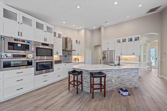 5523 Secluded Oaks Way, Sarasota, FL 34233 - kitchen with appliances with stainless steel finishes, ornate columns, wall chimney range hood, arched walkways, and tasteful backsplash