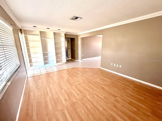 5615 Waneta Pl, Sarasota, FL 34231 - empty room with crown molding, a textured ceiling, light wood finished floors, and built in shelves
