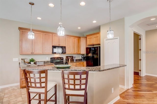 8168 Villa Grande Ct, Sarasota, FL 34243 - kitchen featuring black appliances, arched walkways, light brown cabinetry, recessed lighting, and a kitchen bar