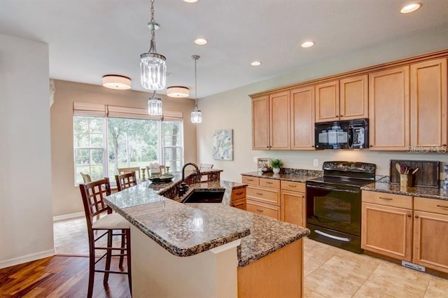 8168 Villa Grande Ct, Sarasota, FL 34243 - kitchen featuring black appliances, recessed lighting, a kitchen island with sink, dark stone counters, and a kitchen bar