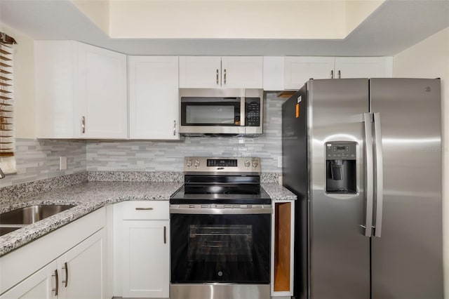 2513 Avenue B Ave B, Unit B, Bradenton Beach, FL 34217 - kitchen featuring appliances with stainless steel finishes, white cabinets, decorative backsplash, and light stone counters