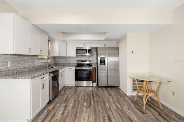 2513 Avenue B Ave B, Unit B, Bradenton Beach, FL 34217 - kitchen featuring appliances with stainless steel finishes, a raised ceiling, dark wood-type flooring, tasteful backsplash, and light stone countertops