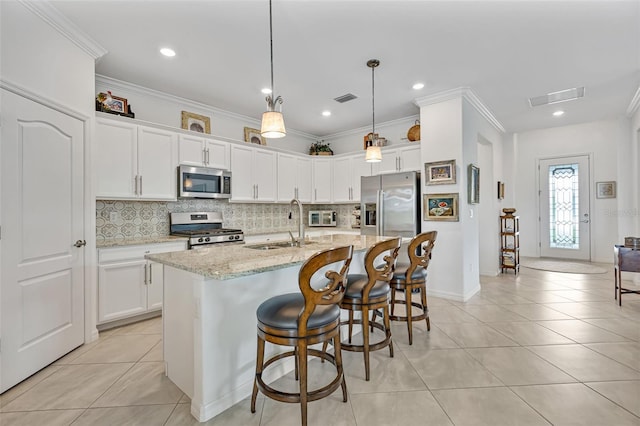 6507 Clairborne Ln, Bradenton, FL 34211 - kitchen with appliances with stainless steel finishes, light tile patterned floors, decorative backsplash, white cabinetry, and a kitchen island with sink