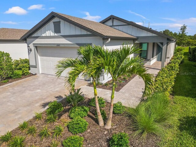 6563 Silverstar Dr, Sarasota, FL 34240 - view of front facade with a garage, decorative driveway, board and batten siding, and roof with shingles