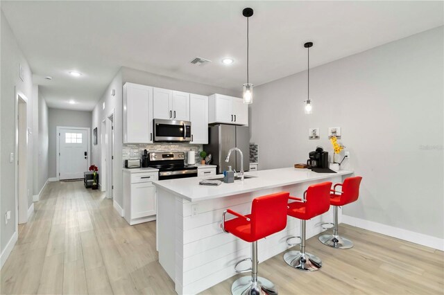 9417 Agate St, Port Charlotte, FL 33981 - kitchen with stainless steel appliances, light wood finished floors, a kitchen bar, backsplash, and baseboards