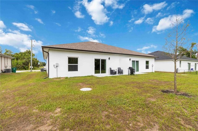 9417 Agate St, Port Charlotte, FL 33981 - back of house featuring stucco siding, a lawn, and central AC unit