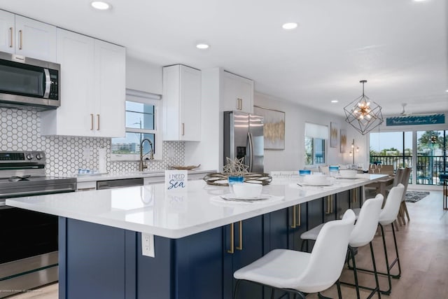 5600 Beach Way Dr Unit 315, Sarasota, FL 34242 - kitchen with stainless steel appliances, a kitchen island, a breakfast bar area, white cabinetry, and backsplash