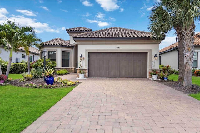 4540 Terrazza Ct, Bradenton, FL 34211 - mediterranean / spanish-style house featuring a tile roof, stucco siding, a front yard, an attached garage, and decorative driveway