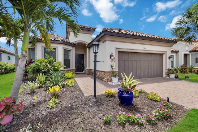 4540 Terrazza Ct, Bradenton, FL 34211 - mediterranean / spanish house with stone siding, stucco siding, an attached garage, a tile roof, and decorative driveway