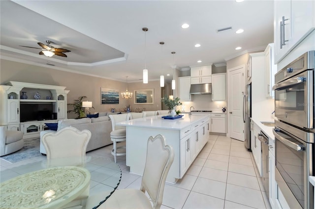 4540 Terrazza Ct, Bradenton, FL 34211 - kitchen featuring appliances with stainless steel finishes, open floor plan, under cabinet range hood, an island with sink, and light countertops