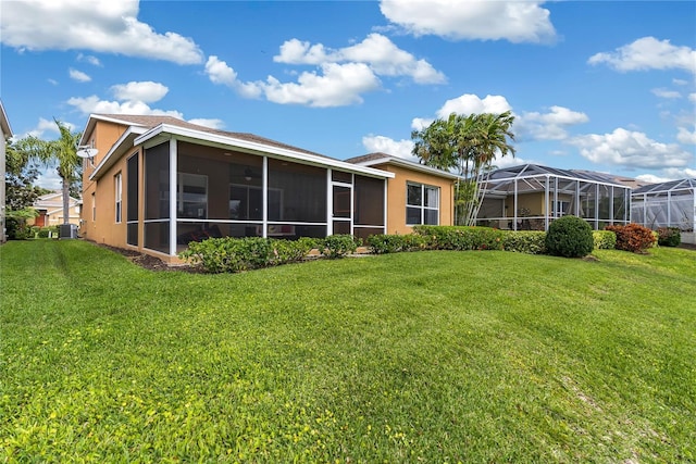 3671 Summerwind Cir, Bradenton, FL 34209 - rear view of house with central AC unit, stucco siding, a lawn, and a sunroom