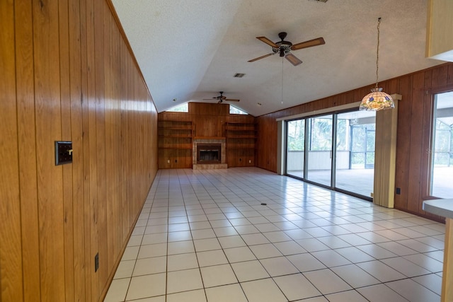 3804 65th St E, Bradenton, FL 34208 - unfurnished living room with wooden walls, ceiling fan, lofted ceiling, a glass covered fireplace, and a textured ceiling