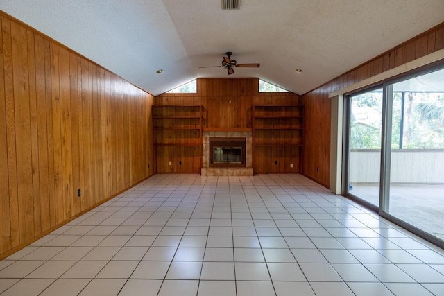 3804 65th St E, Bradenton, FL 34208 - unfurnished living room with wooden walls, vaulted ceiling, ceiling fan, a tiled fireplace, and built in shelves