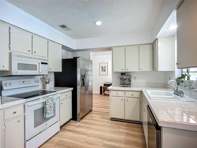912 Ponderosa Pine Ln, Sarasota, FL 34243 - kitchen featuring appliances with stainless steel finishes, tile countertops, a textured ceiling, light wood finished floors, and recessed lighting