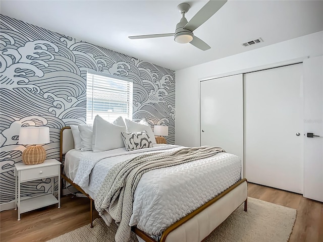 912 Ponderosa Pine Ln, Sarasota, FL 34243 - bedroom with wallpapered walls, a closet, light wood-type flooring, an accent wall, and ceiling fan