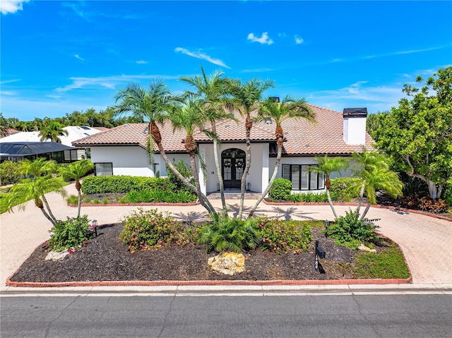 1484 Seafarer Dr, Osprey, FL 34229 - mediterranean / spanish-style house with stucco siding, french doors, a chimney, a tiled roof, and decorative driveway