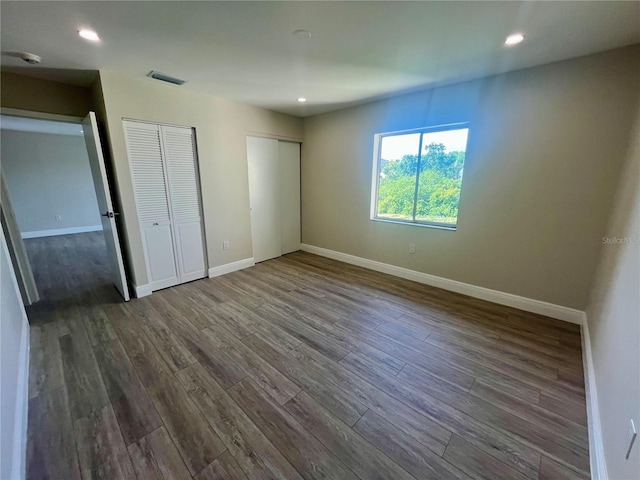 2636 Hidden Lake Dr N Unit G, Sarasota, FL 34237 - unfurnished bedroom featuring multiple closets, wood finished floors, and recessed lighting