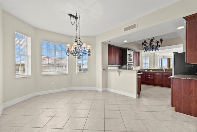 5100 Jessie Harbor Dr Unit 701, Osprey, FL 34229 - kitchen with a chandelier, stainless steel appliances, reddish brown cabinets, and a peninsula