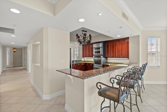 5100 Jessie Harbor Dr Unit 701, Osprey, FL 34229 - kitchen featuring a chandelier, light tile patterned flooring, recessed lighting, dark stone countertops, and a breakfast bar area