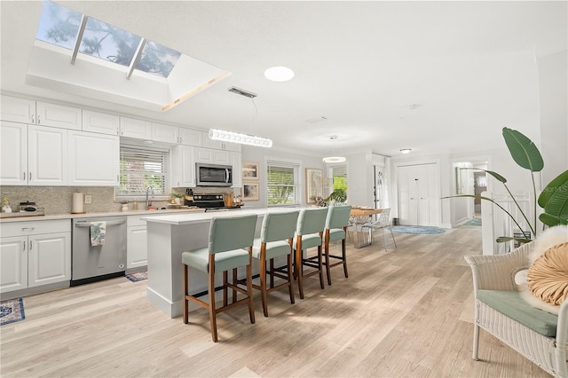 1112 Montezuma Dr, Bradenton, FL 34209 - kitchen with stainless steel appliances, a kitchen island, decorative backsplash, light countertops, and light wood-style floors