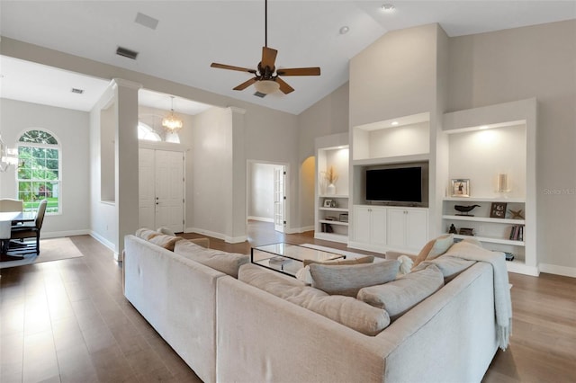 8102 Waterview Blvd, Lakewood Ranch, FL 34202 - living room featuring wood finished floors, built in features, high vaulted ceiling, ceiling fan, and a chandelier