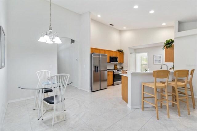 4845 Post Pointe Dr, Sarasota, FL 34233 - kitchen featuring stainless steel appliances, a chandelier, brown cabinetry, a peninsula, and recessed lighting