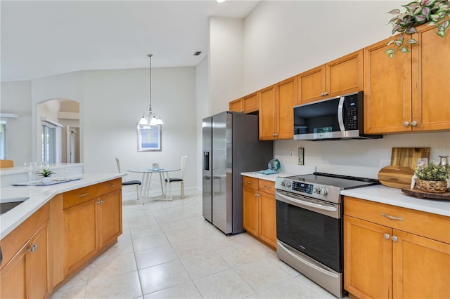 4845 Post Pointe Dr, Sarasota, FL 34233 - kitchen featuring appliances with stainless steel finishes, light countertops, brown cabinetry, a high ceiling, and light tile patterned floors
