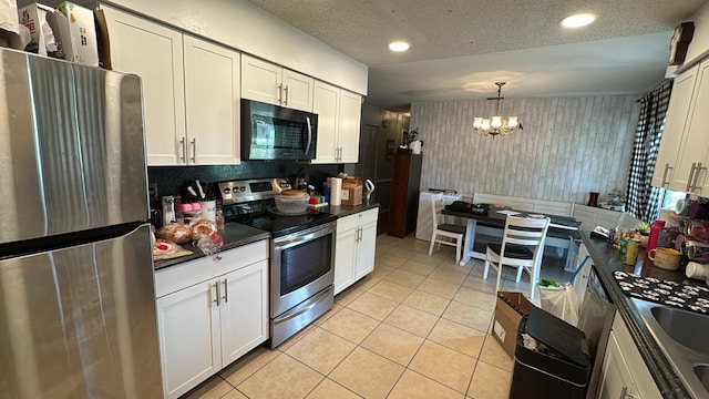 23067 Elmira Blvd, Punta Gorda, FL 33980 - kitchen with stainless steel appliances, a chandelier, dark countertops, light tile patterned floors, and white cabinets