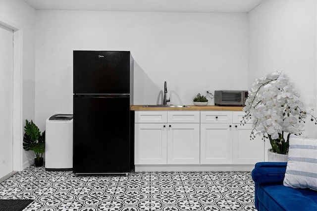2866 E Rainbow Cir, Sarasota, FL 34231 - kitchen with freestanding refrigerator, butcher block counters, white cabinetry, and light tile patterned floors