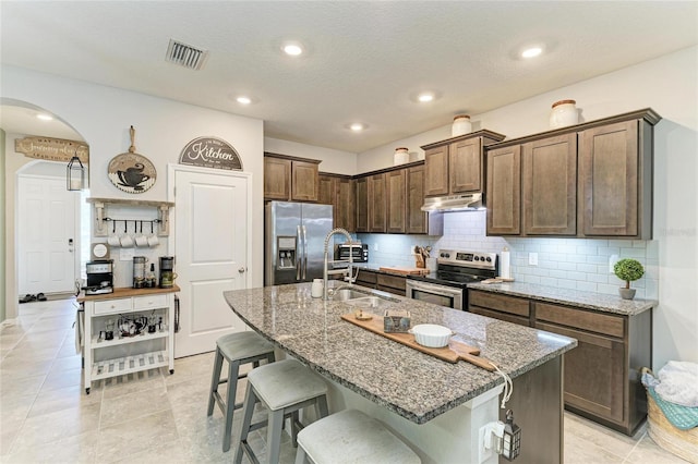 8676 Ice Wine St, Sarasota, FL 34238 - kitchen with appliances with stainless steel finishes, under cabinet range hood, a kitchen breakfast bar, light stone countertops, and recessed lighting
